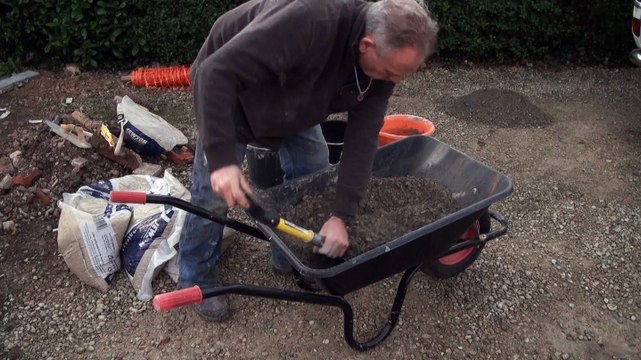 Mixing concrete in a wheelbarrow to lay concrete edging stones or garden paths