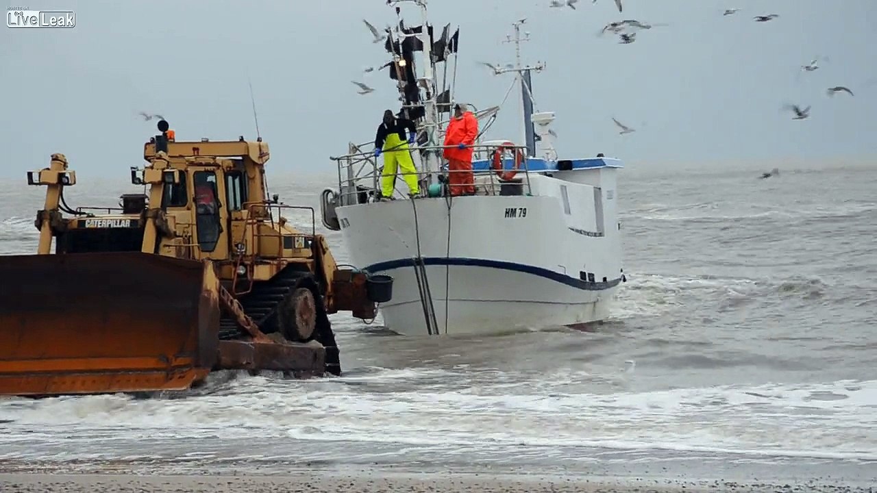 Fishingboat getting help ashore from a bulldozer. (Volume warning)