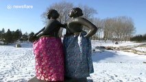 Statues wearing traditional Chinese robes in beautiful, snow-covered park