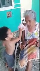 طفل يُطعم جدته العجوز الجالسة على مقعد متحرك