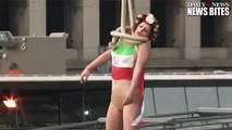 A topless woman with the Iranian flag painted on her chest staged a mock execution