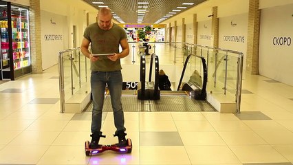 Holding the iPad's the balance, he rides a Hoverboard.