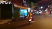 Dog carries owner's umbrella, while the both ride scooter