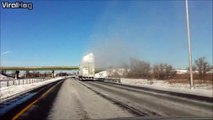 Un camion couvert de neige passe sous un camion et provoque une explosion de poudreuse sur l'autoroute