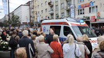 Alarmowo karetka pogotowia ratunkowego przebija się przez tłum podczas pogrzebu w Gdyni