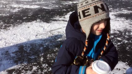 Young boy amused by sinking cars that parked on ice