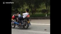 Four-year-old boy drives motorbike as dad reclines behind