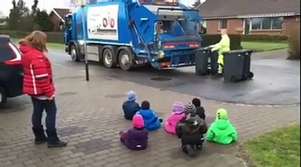 Des enfants subjugués regardent des éboueurs