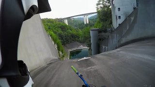 Il descend le mur d'un barrage hydraulique à vélo