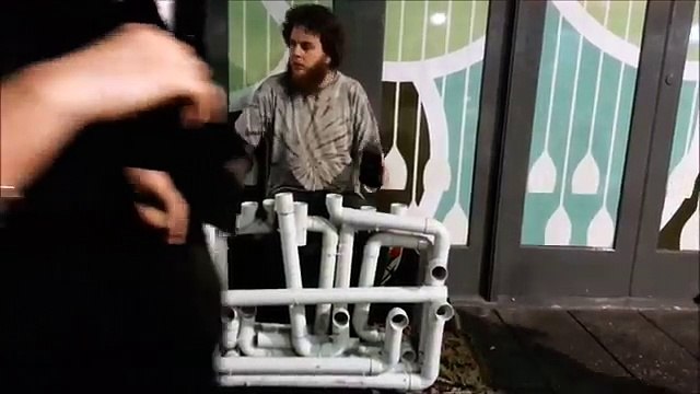 Уличный музыкант играет на водопроводных трубах