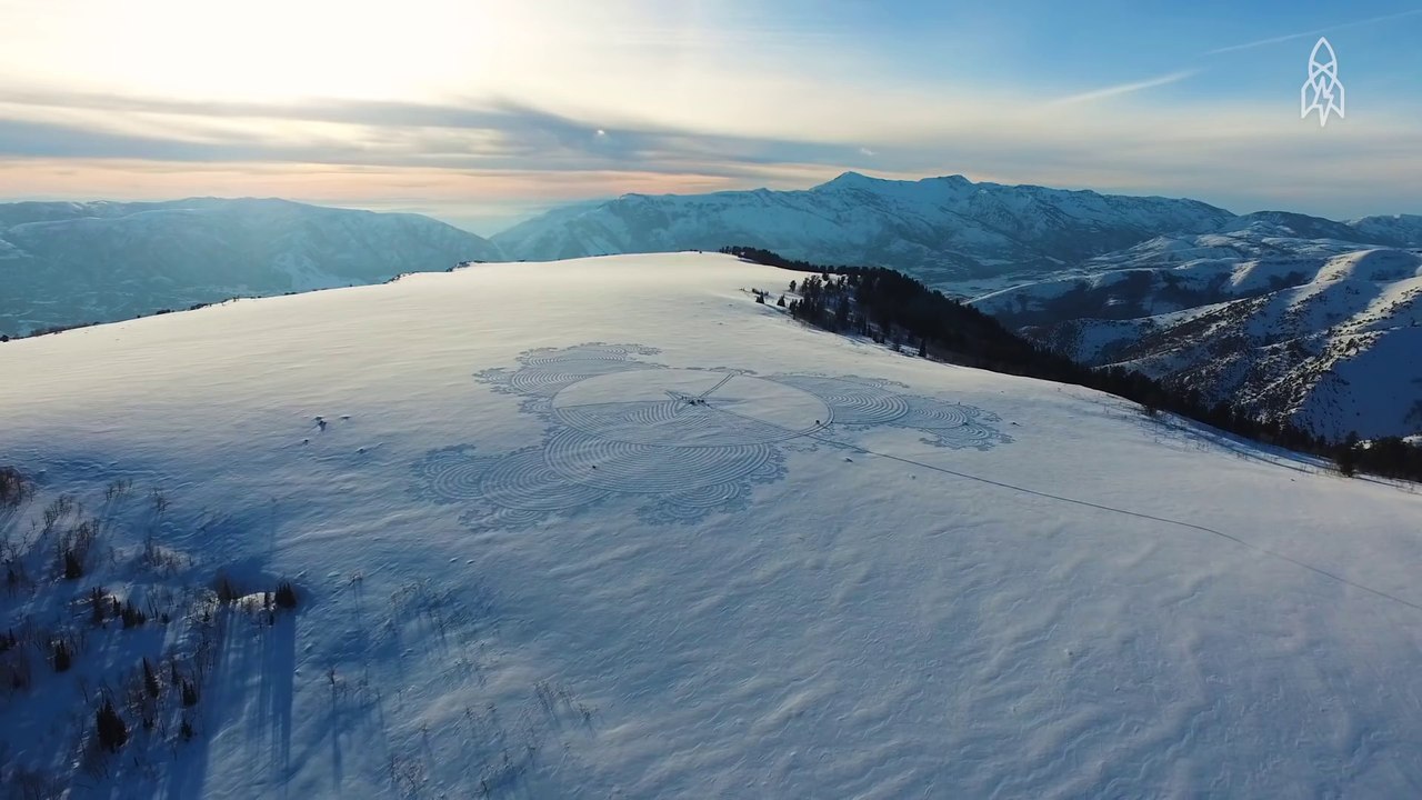 Un artiste crée des motifs géants dans la neige, visible en altitude en hélicoptère