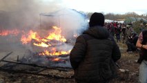Démantèlement de la jungle de Calais, les migrants éteignent un feu de cabane