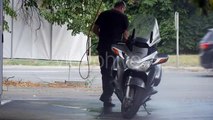 Man With Hosepipe in His Hands Carefully Washes His Silver Motorbike at the Carwash on the