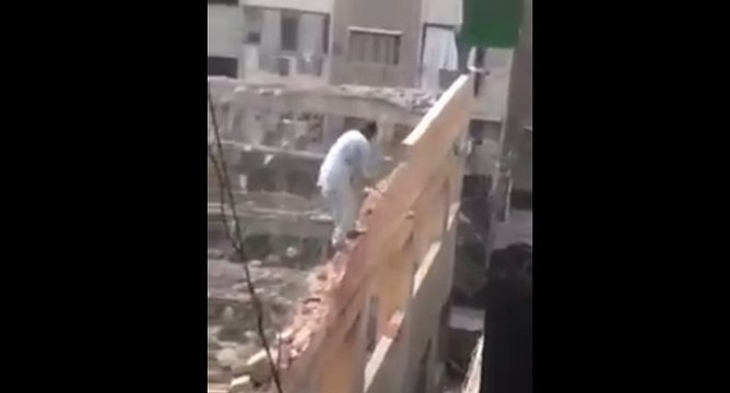 Un homme au-dessus du vide détruit un mur à coup de masse