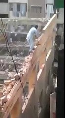 Un homme en equilibre sur un mur lors de la démolition d'un bâtiment
