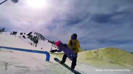 Il fait des figures en snowboard avec un bébé dans les bras