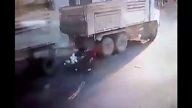 Deux gars sur un scooter glissent et terminent sous les roues d’un camion