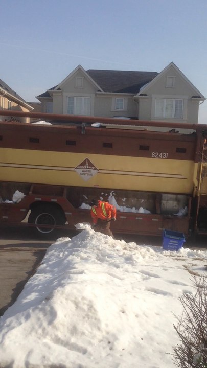 Garbage Man Shoveling Snow Into The Truck
