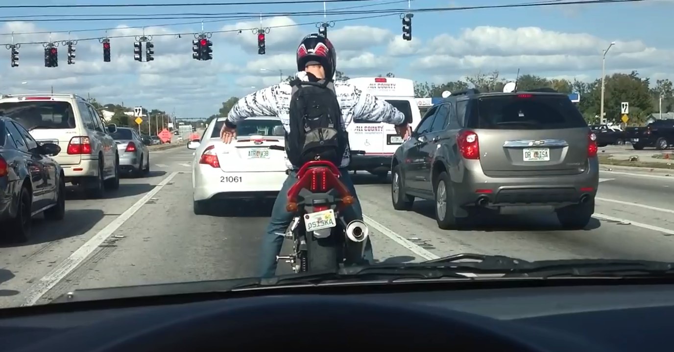 Un motard danse sur sa moto au feu rouge