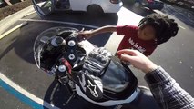 Un motard laisse un enfant démarrer sa moto. Trop sympa