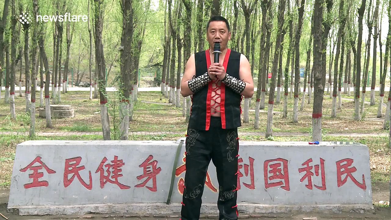 Martial artist uses his stomach to blow dart out and pop balloon behind glass