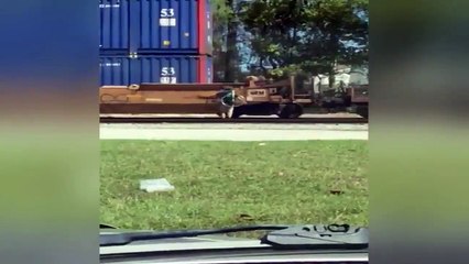 Un livreur à vélo monte sur un train en mouvement pour traverser une voie ferrée