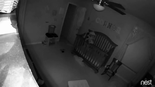 Bébé tient en équilibre debout sur la barrière de son lit