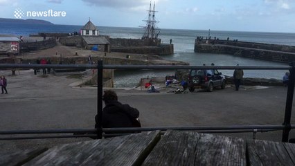 An old fashioned ship sails into a UK harbour