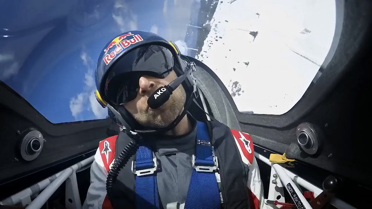 Un avion de voltige slalome dans un champ d'éoliennes