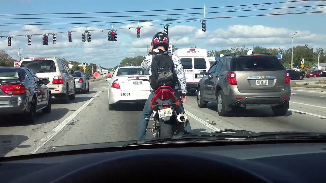 Un motard danse sur sa moto au feu rouge