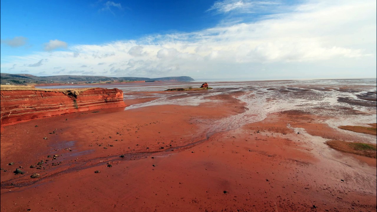 Red sand, blue skies, and white clouds.