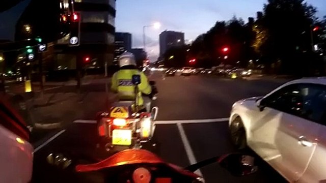 Cette voiture grille un feu rouge à coté d'un motard de la police..