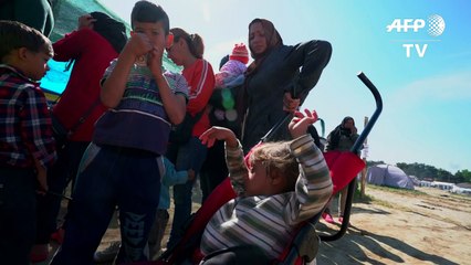 عدد من المتطوعين يساعدون الأطفال في مخيم ايدوميني على الاستحمام