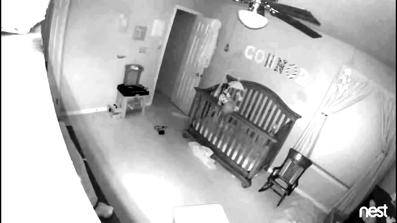 Un bébé tient en équilibre debout sur la barrière de son lit