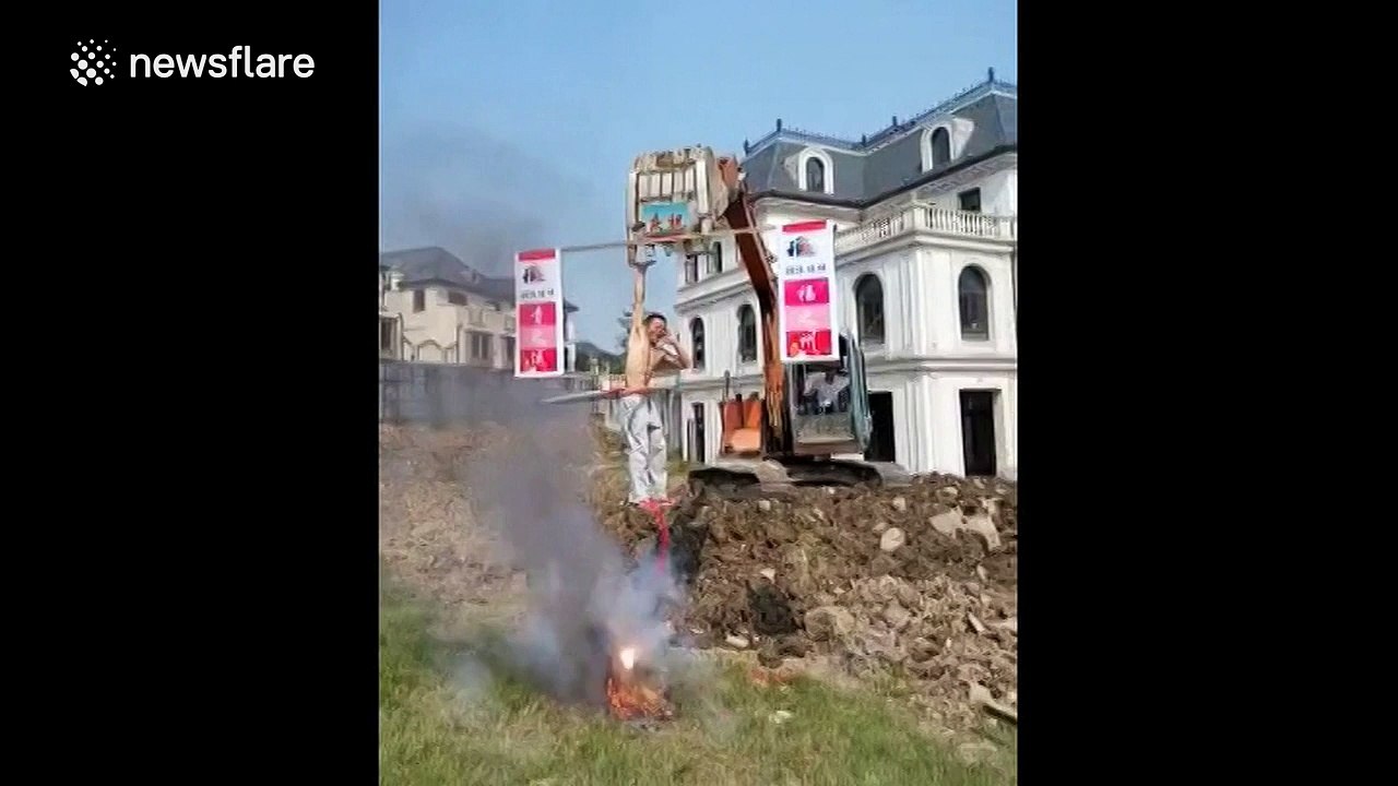 Man hula-hoops while being lifted into the air by a JCB