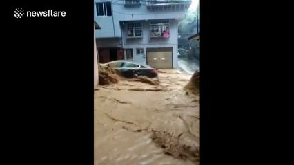 Gushing floodwater rushes down a street in China