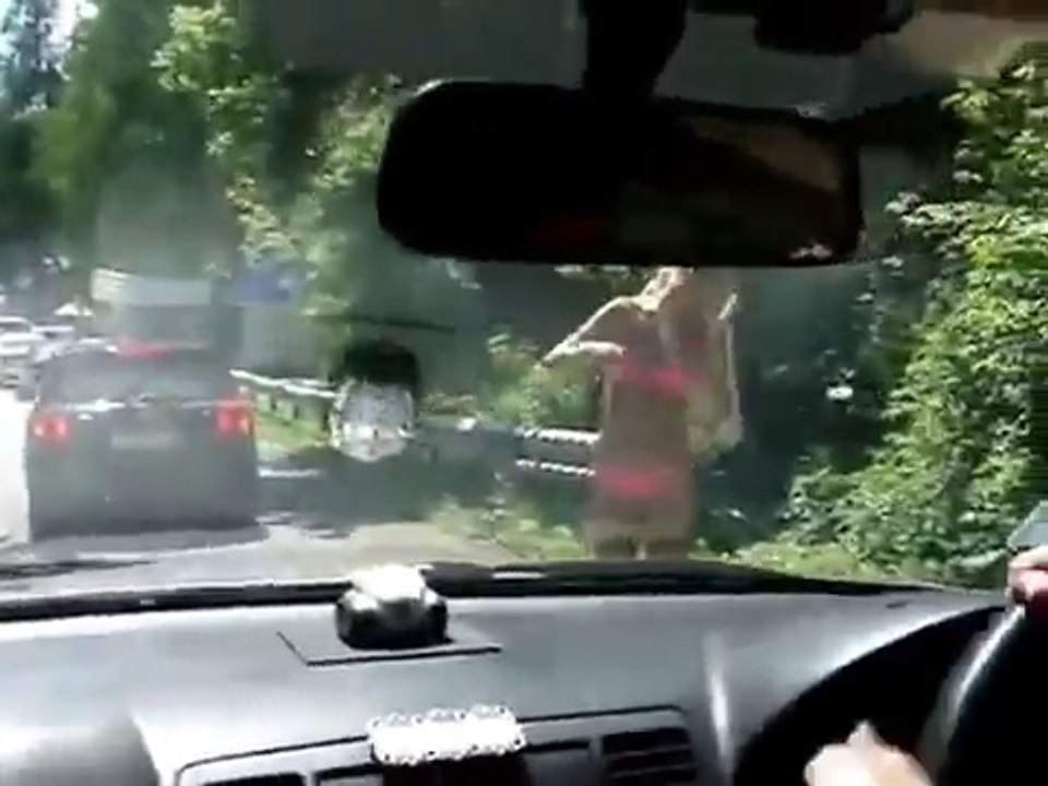 Девушка в купальнике танцует на дороге.