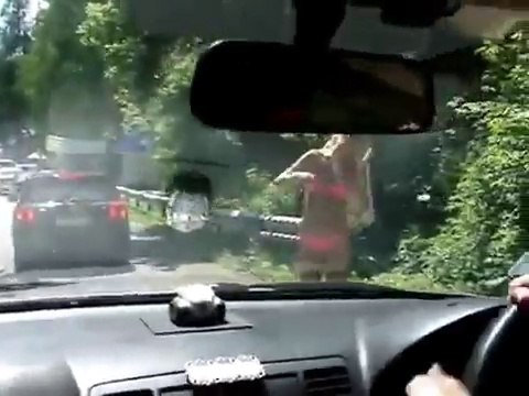 Девушка в купальнике танцует на дороге.