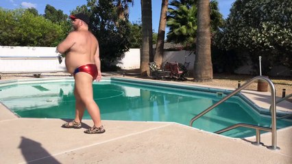 Un homme danse au bord d'une piscine en maillot de bain