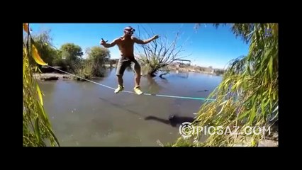 Crazy man walking on rope while hungry alligator watching to him below