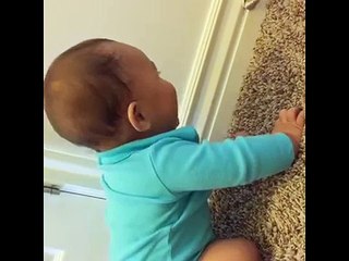 Cute baby laughs while playing with a spring door stop