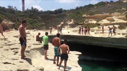 Собака прыгает со скалы в воду