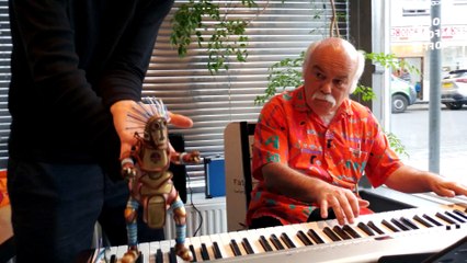 Une marionnette danse avec un pianiste qui joue dans un restaurant...