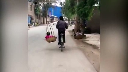 Father balances two children while riding a bicycle