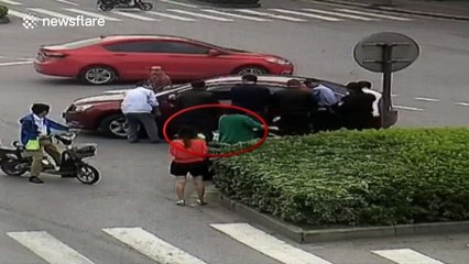 A group of people lift up a car to release a man trapped under it