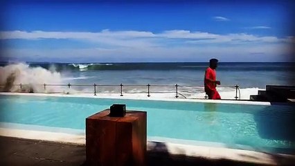 Une grosse vague s’abat subitement sur la piscine d’un bar de bord de mer (Bali)