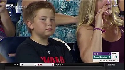 Un enfant fixe une caméra pendant un match de baseball