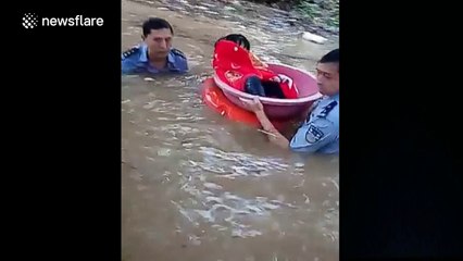 Police use foot basin to help child cross flooded street
