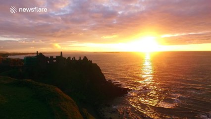 Beautiful sunset with ocean glitter path over Dunluce Castle in Northern Ireland