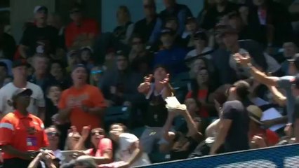 Une spectatrice récupère une balle de baseball avec sa nourriture